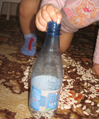ребенок бросает фасоль в бутылку