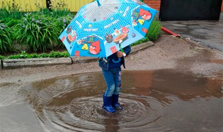 ребенок играет после дождя в луже